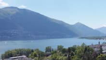 Mountain lake view, buildings, trees, mountains in the distance, clear blue sky