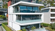 Modern 3-story house, glass facade, multiple balconies, mountain view