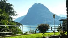 overlooking a mountain and lake, with a metal railing, street lamp, and lush greenery