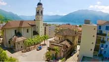 Church with a bell tower, several houses, road, lake, mountains in the background