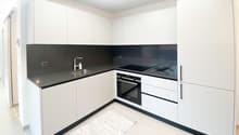 modern kitchen, white cabinets, black countertops, stainless steel sink, silver faucet, black oven, white tile flooring