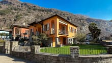 2-story house, orange exterior, brick wall foundation, multiple windows, fenced lawn, car parked, balcony on the first floor