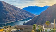 lake nestled between the mountains, residential houses with tiled roofs, dam on the lake, trees and shrubs