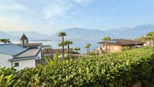 House with a view of the lake and mountains, solar panels on the roof, surrounded by greenery