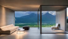 Spacious living room with large floor-to-ceiling windows offering a stunning view of the mountainous landscape outside. The room features a comfortable sofa, a coffee table, and an armchair, creating a cozy and relaxing atmosphere. The minimalist and mode