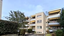 4 story building, beige exterior, multiple balconies, awnings, greenery
