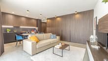 Modern living area with beige couch, white rug, coffee table, TV unit, dining table with chairs