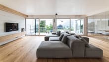Wooden floor, large grey couch, TV, sliding glass doors to balcony