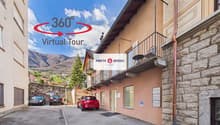 Building with stone walls, balcony with railings, parked cars, and a sign indicating a virtual tour.