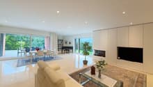 modern style, white tiled floor, dining area with table and chairs, living area with couch, carpet, table, shelves, piano, fireplace, tv, glass windows leading to terrace