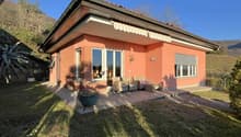 Single-story house, brick walls, red roof, large windows, outdoor seating area, garden, patio