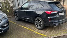 Black Kia Sorento SUV parked on the street, with a grey car parked next to it. The SUV has a rear spoiler and large wheels.