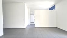 empty room, gray tile flooring, white walls, electrical outlets, white refrigerator in another room