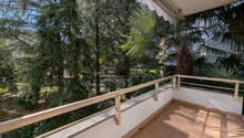 covered balcony, metal railings, tiled floor, surrounded by greenery