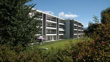 Modern apartment building with multiple floors, balconies, and a well-maintained garden area.