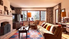 Fireplace, large windows, couch, coffee table, armchair, TV, rug, lamps, picture frames, decorative items