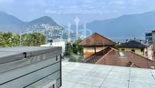 Terrace with tile floor, covered spa, houses in the background, glass railing, mountains in the distance