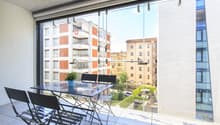 modern furnished balcony, large windows, view of other buildings, outdoor dining table and chairs