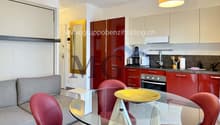 modern kitchen with red cabinets, black countertops, large dining table, modern chairs, glass, microwave, dishwasher, washing machine