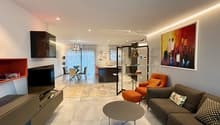 Modern and bright living room with a sofa, coffee table, flat screen TV, and paintings on the wall