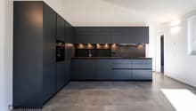 modern kitchen with black cabinets, tiled flooring, integrated oven and sink, under-cabinet lighting, large countertop