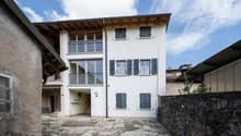 white building, 3 floors, multiple windows, balconies, stone pathway, stone wall
