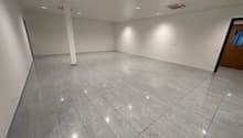 white walls, gray floor tiles, column in the middle, white ceiling, lights on the ceiling, empty room