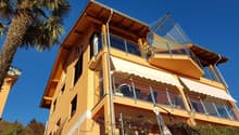 3 story house, yellow exterior, multiple balconies, glass railings, awnings, fenced yard