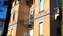 Two-story building, beige color, lots of balconies, plants