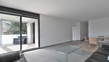 Modern and open living room with sliding glass door leading to balcony, leather couches, coffee table, and dining table with chairs