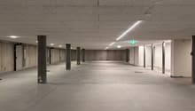 Empty parking lot with concrete floor, metal poles, and ceiling lights