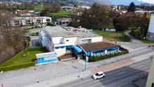2-story building, parking in front of it, blue windows, brown roof