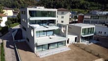 Modern building with glass walls, multiple balconies, roof terrace
