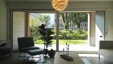 modern living room with sliding glass doors, large windows, modern furniture, plants, marble coffee table, rug, lamp