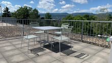 Outdoor table and chairs on a balcony with a view of the mountains