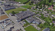 Large industrial/commercial complex with multiple buildings, parking lots, and surrounding residential and green areas.