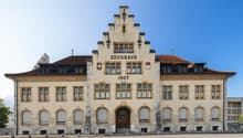 Zeughaus from 1907, large building with multiple windows, wooden doors, and a clock on the tower.