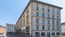 Large office building, stone facade, multiple glass windows, modern architecture, street sign in front, urban setting