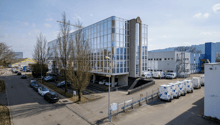 modern office building, glass facade, multiple floors, parking lot, multiple vehicles