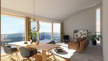 Spacious open-plan living and dining area with large windows offering a scenic view. The room features a wooden dining table with modern chairs, a comfortable leather sofa, and a decorative pendant light. The space also includes a balcony or terrace acces