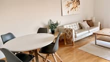 living room with sofa, round dining table, dining chairs, round coffee table, potted plant, wooden flooring, framed art on wall
