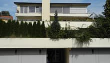 2 story house, white exterior, raised ground floor, garage, balcony, green roof