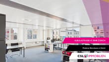 Open floor plan, desks, chairs, monitors, bookshelves, cabinets, radiators, carpeted floor, windows
