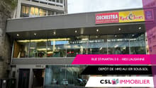 Building located at Rue St-Martin, 1003 Lausanne. Large entrance with glass walls, staircase, glass doors, and storefront with an escalator. A shop sign for 'ORCHESTRA' and 'King Jouet' is present on top. Address and real estate information displayed on t
