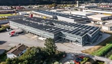 industrial building with solar panels, parking lot, and surrounded by greenery