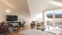 Living room with large glass window, balcony, wooden floor, large sofa, coffee tables, armchairs, television