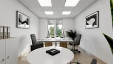 This image shows a modern and minimalist office space. The room has a white ceiling with recessed lighting panels, white walls, and a tiled floor. There is a large round white table in the center of the room, surrounded by black office chairs. Two framed
