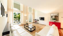 Leather couch, glass coffee table, television, red cabinet, mirror, wooden floor, white walls, picture frames, white curtains, balcony, outdoor furniture