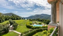 overlooking a wide green landscape with a swimming pool and mountains in the background