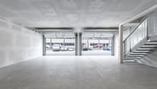Empty garage with two open doors, concrete floor, white walls, metal staircase
